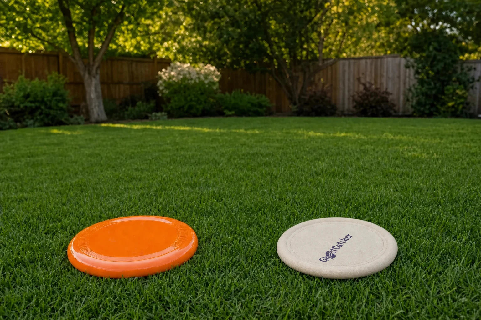 Human view: an orange disc and the ivory GHOSTCATCHER disc with its logo on grass